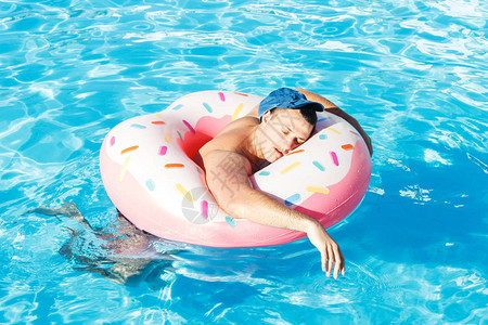 在游泳池里游泳的充气甜圈上喝醉背景图片