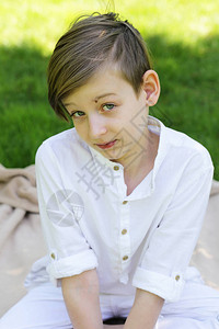 金发男孩在绿草地上穿着白衣的图片