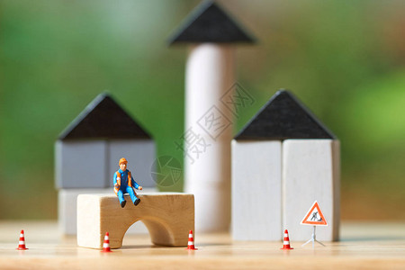 微型人建筑工人坐在木头上投资分析住房或动产投资图片