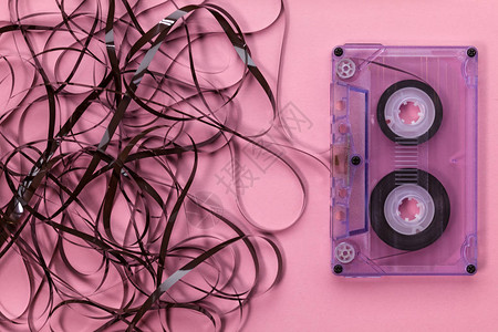 粉红背景的紧凑录音带与胶带挂在一团图片