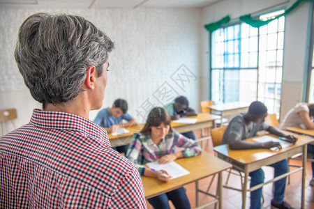 教师检查学生在十几岁的教室里进行学背景图片