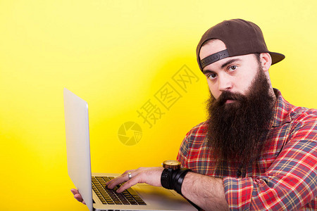 黄色背景中戴着帽子手里拿着笔记本电脑的长胡子图片