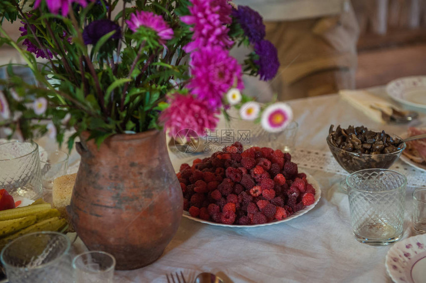 用鲜花和覆盆子盘装饰的乡村餐桌图片