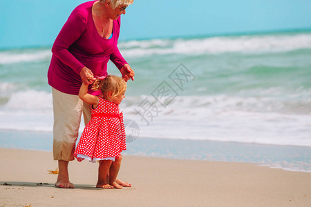 快乐的祖母和小孙女在海滩上图片