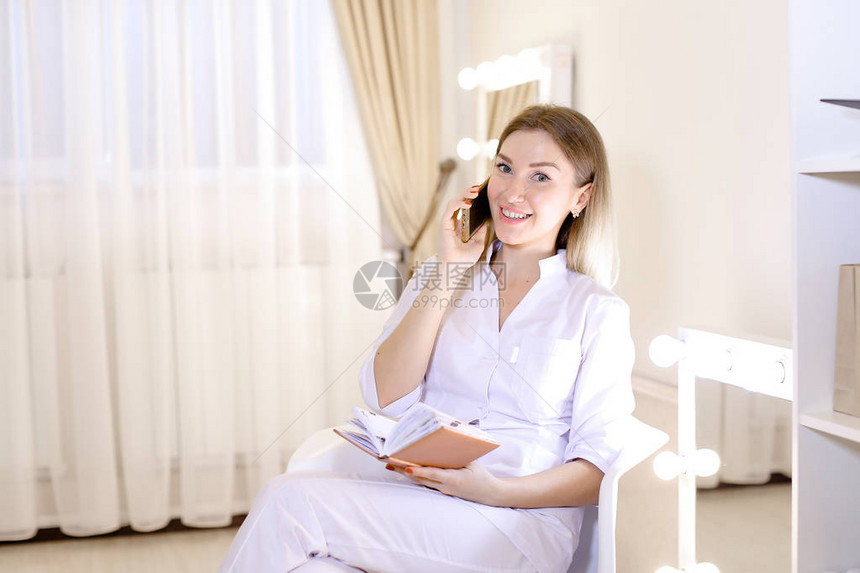 女专业皮肤科医生在柜子里用智能手机说话通过手机预约图片