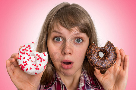 迷人的女人在两个甜圈之间做出抉择与粉图片