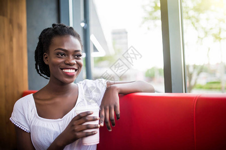 一个微笑的非裔美国妇女喝图片