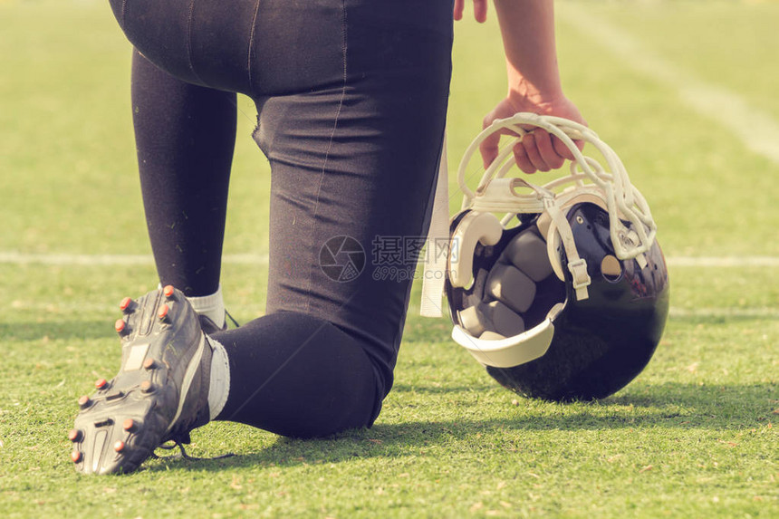 美国足球运动员单膝站在绿图片