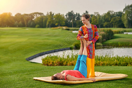 由治疗师接受传统泰式伸展按摩的成熟女士女泰式按摩治疗师在草坪上与成熟图片