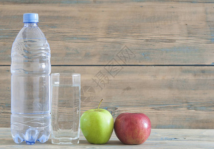 木制桌上的塑料水瓶和水杯健康饮食和健身图片