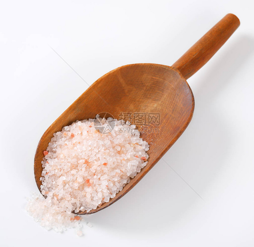 白色背景上的一勺粗粒喜马拉雅盐图片
