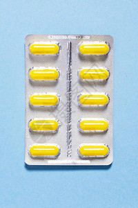 蓝色背景包装中有药物的黄色胶囊图片
