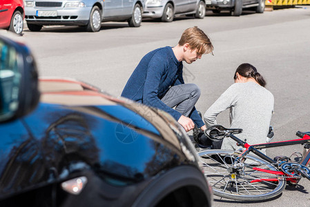 帮助他人的年轻男子在街头自行车事故中遭受痛苦的紧张或骨折后图片