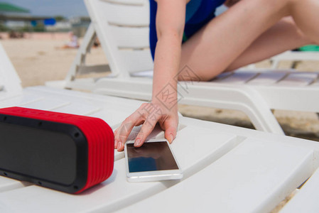 妇女享受无线蓝牙小工具的假期在海滩上使用图片