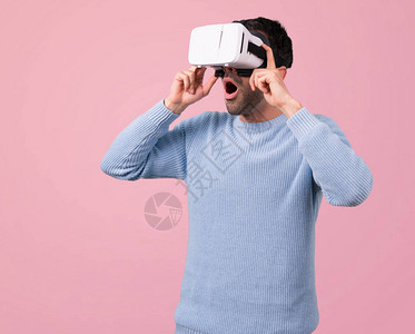 使用VR眼镜穿蓝色毛衣的男人关于粉红色背景的图片