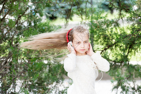 女孩在夏日公园随着音乐跳舞小孩在户外的耳机中享受音乐长着飞舞的头发的儿童舞者旋律声音和mp3夏天背景图片
