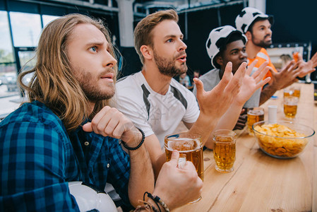 一群穿着足球帽喝啤酒和在酒吧看足球比赛的男足球迷图片