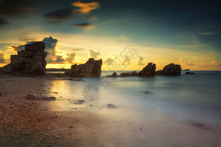 泰国Rayong海滩日出时自然石拱门的海景图片