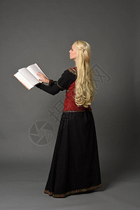 穿着红色和黑色幻想中世纪长袍的金发美女全长肖像在灰色背背景图片