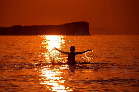 美丽的女人在日落时溅入大海在海中的女孩剪影海滩度假图片