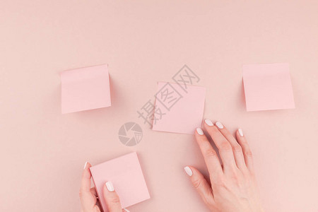 创意平躺的工作台照片与千禧粉贴纸在女人手中模拟并粘贴在墙上背景图片