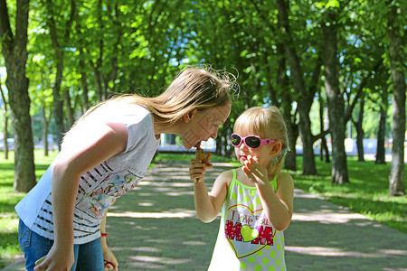 妹给姐吃冰淇淋姐妹情谊两个小姐妹在夏日公园里图片