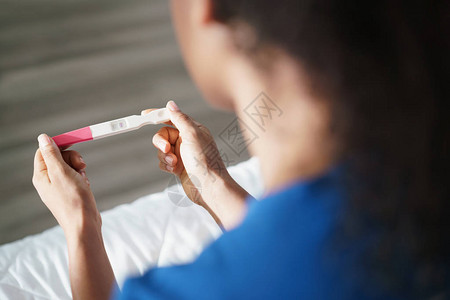 在床上感到焦虑的忧郁的年轻西班牙裔女黑人女孩接受负面怀孕测试手图片