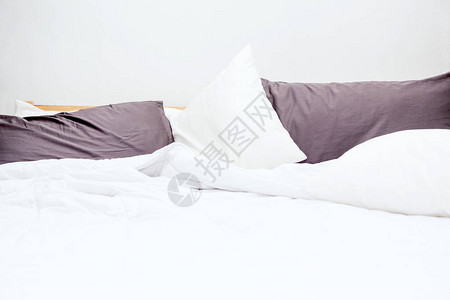 凌乱的床和白色的床单和枕头图片