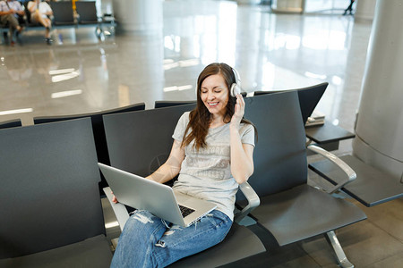 年轻的微笑旅行者旅游女戴着耳机在笔记本电脑上听音乐图片