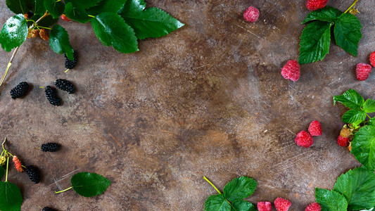 食物背景成熟的夏季浆果覆盆子桑椹和绿色湿叶在复古背景上为您的项目腾图片