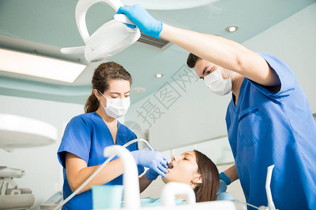 牙医用牙科工具治疗病人而男同事在图片