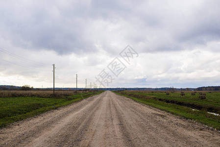 透过绿地的乡村道路在阴云的一天图片