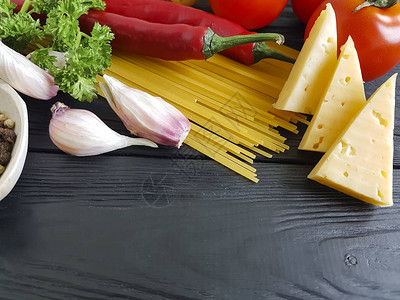 意大利面黑色木制背景上的大蒜西红柿图片