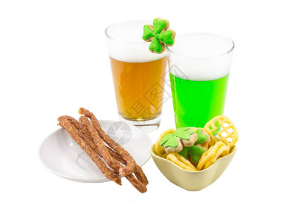 瘦肉香肠辣薯条和两杯啤酒和绿色高白色泡沫和三叶草饼干在白色背景图片