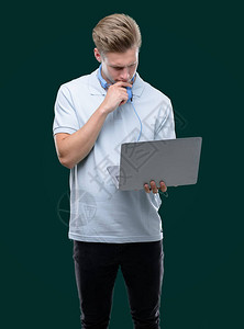 年轻英俊的金发男子用笔记本电脑严重的脸孔思考问题图片
