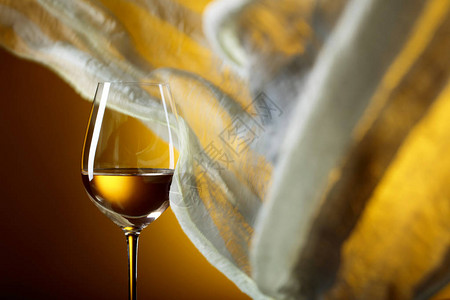 黄色背景的白葡萄酒杯子黄色织物在风中飘图片
