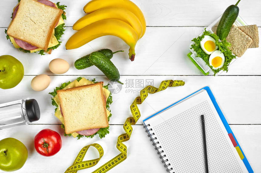 配有复制空间和健康早餐的顶级规划笔记本三明治加火腿和奶酪鸡蛋黄瓜番茄和白木图片