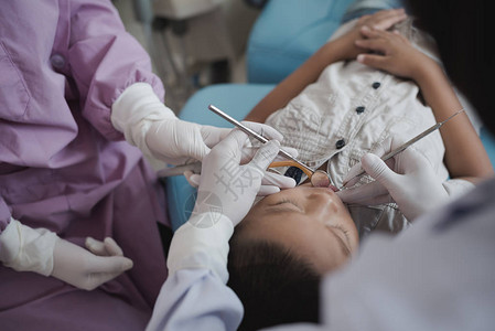 拿着牙科工具的牙医的手给躺在医院牙科椅上的图片