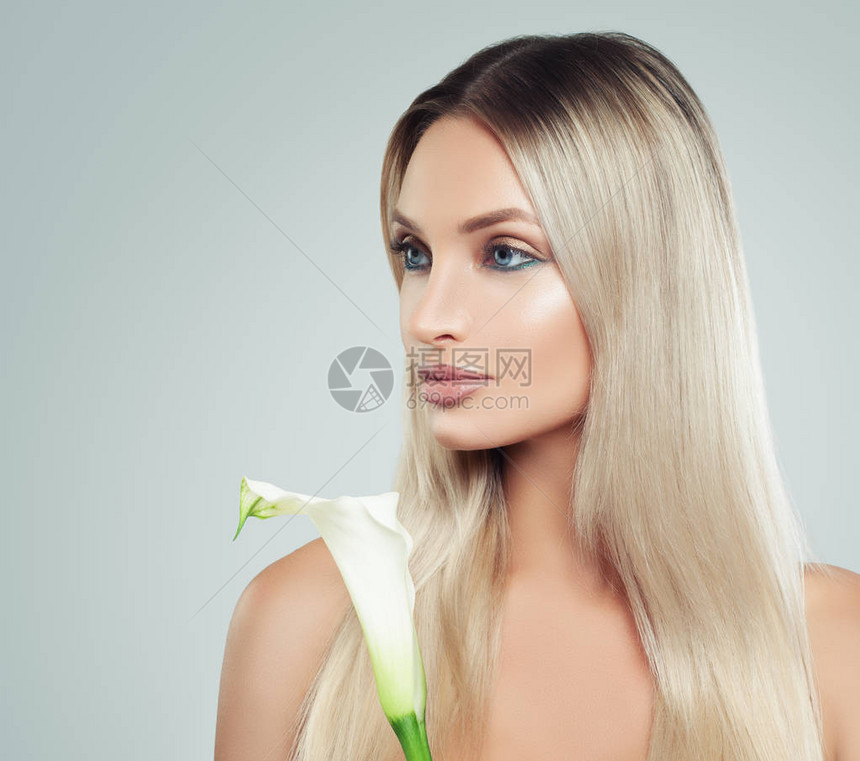 可爱的年轻女子与新鲜的皮肤健康的头发和她手中的百合花面部护理美容护肤图片