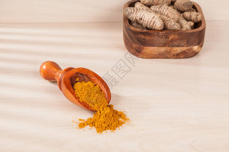 木制背景上的姜黄粉和新鲜姜黄图片