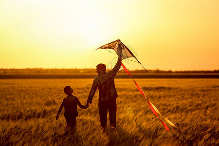 快乐的父亲和儿子在日落时图片