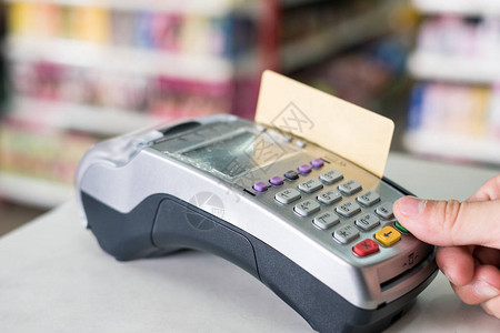 在超市付款终端上用打刷信用卡的手图片