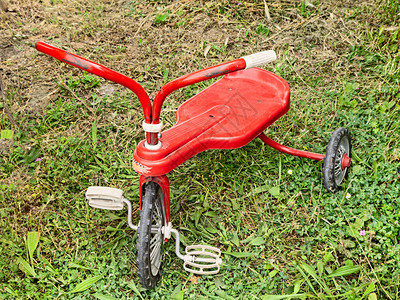 古老的玩具红色三轮车供草地图片