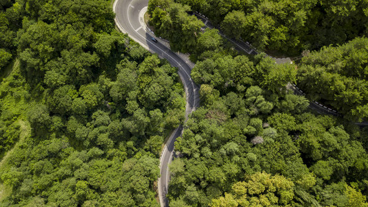 汽车沿着蜿蜒的山口公路穿过俄罗斯索契森林的空中库存照片背景图片