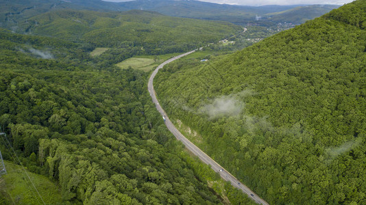 汽车沿着蜿蜒的山口公路穿过俄罗斯索契森林的空中库存照片背景图片