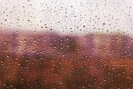 窗玻璃上的雨滴水在城市风景背景图片