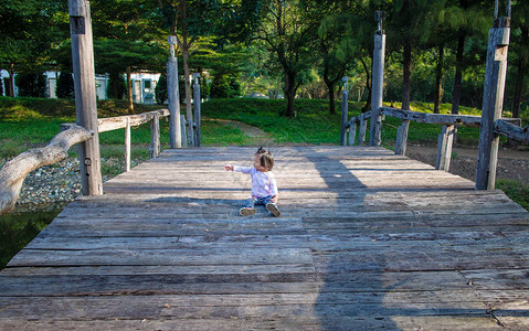 小女孩坐在木桥上指点图片