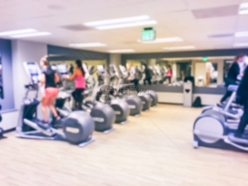 老式模糊的人在现代健身房的椭圆机和健身车上锻炼美国四星级酒店设施室内耐力设备配备训练器械的图片