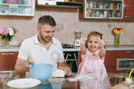 小女孩帮助男人在餐桌上煮圣诞姜饼和撒面粉背景图片