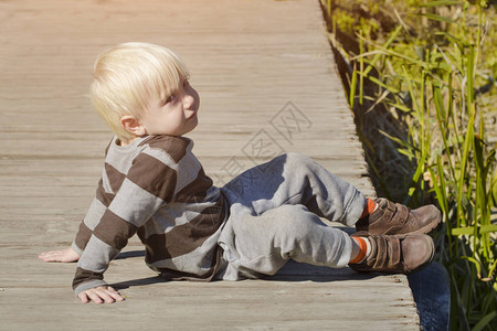 金子小男孩坐在码头上秋天阳图片